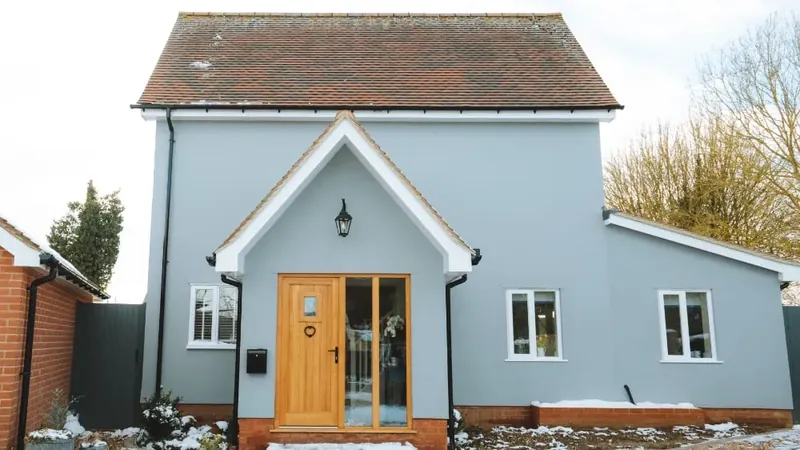 Extended and refurbished detached cottage with pale blue render and oak porch in Kersey, Suffolk